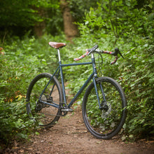 Load image into Gallery viewer, Bicycle on a forest path surrounded by greenery